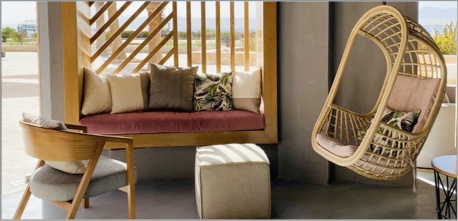 Design idea for a porch space, with a dark colored couch, an ottoman, and a hanging chair